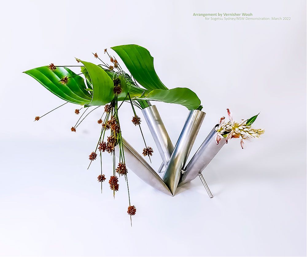 Strelitzia leaf with Club grass and Bromeliad flower in metal container 